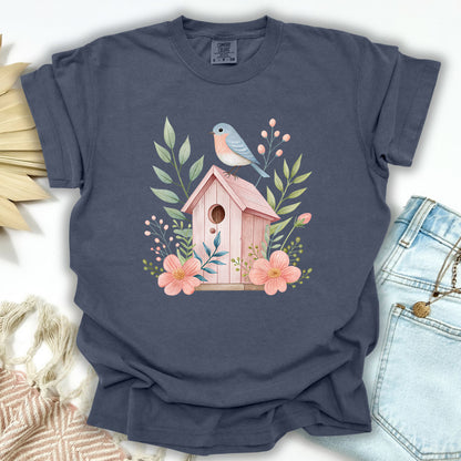 Denim S garment-dyed t-shirt with a watercolor pink birdhouse, blue bird, and floral design.