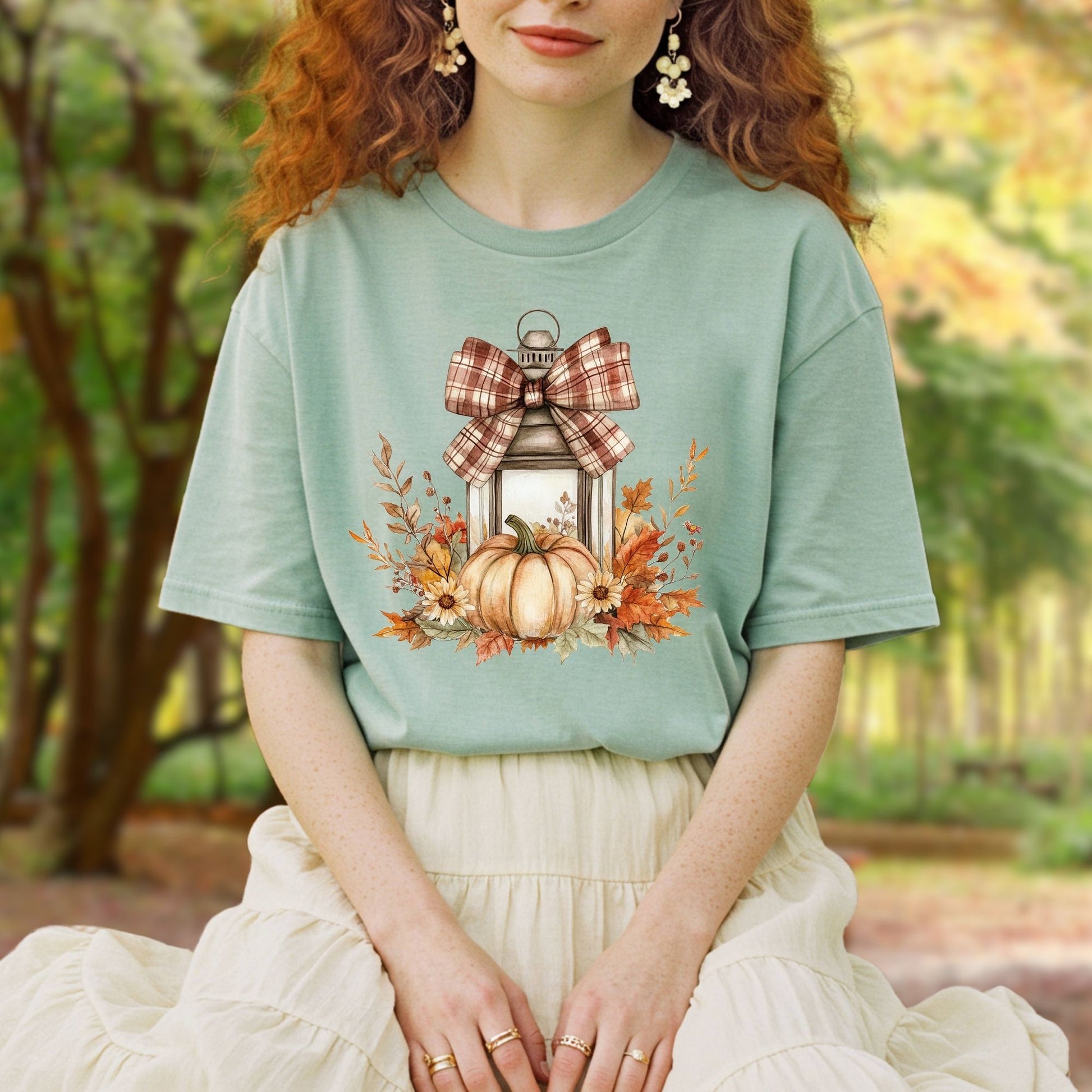 Garment-dyed tee with a rustic autumn lantern, pumpkin, sunflowers, and plaid bow design.