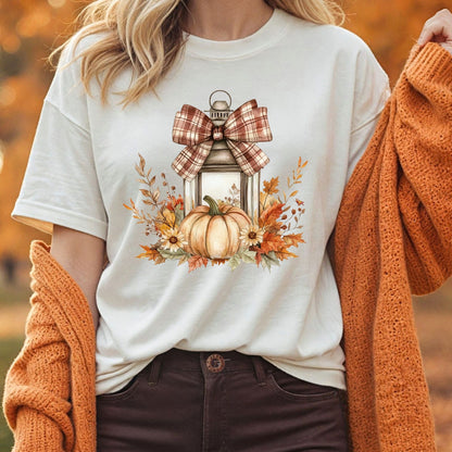 Relaxed-fit, cream garment-dyed tee with a rustic lantern, plaid bow, pumpkin, and fall foliage design.