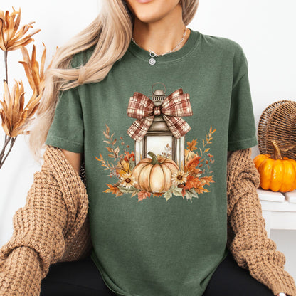 Garment-dyed green tee with a rustic autumn lantern, plaid bow, pumpkin, and fall foliage design.