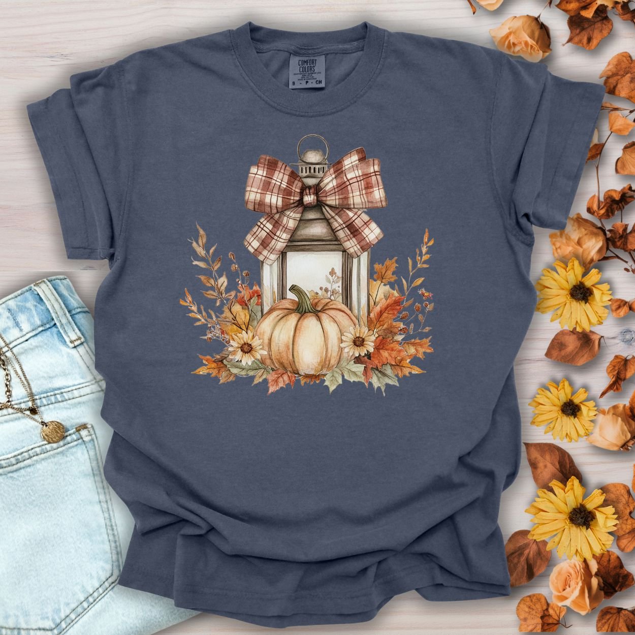 Denim blue garment-dyed tee with a rustic lantern, pumpkin, sunflowers, and plaid bow design.