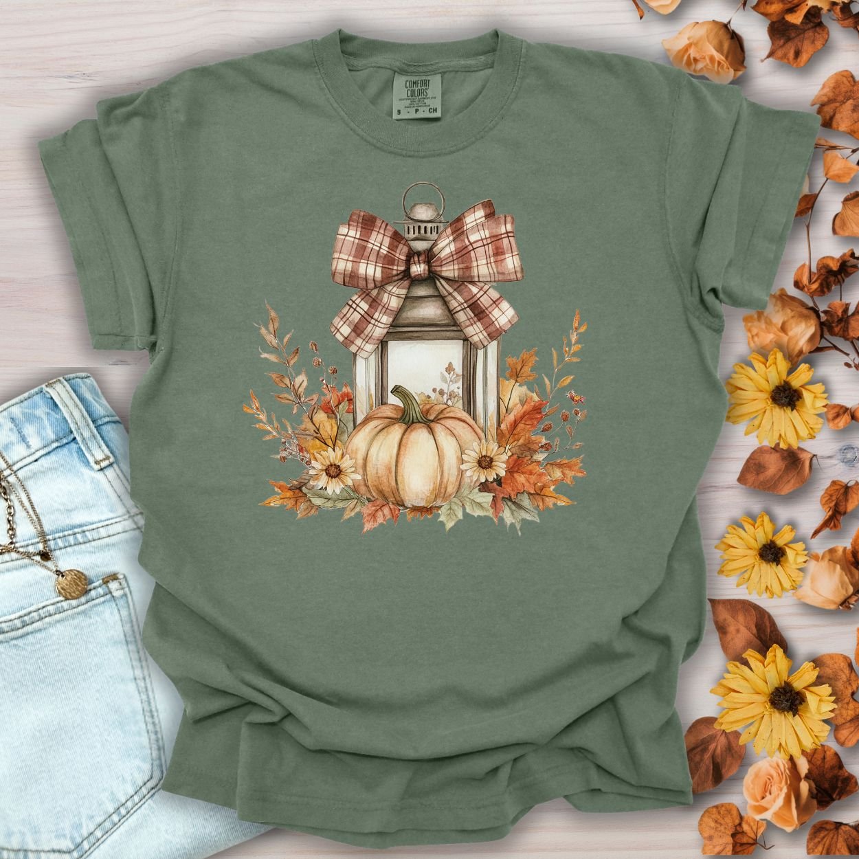Moss green garment-dyed tee with a rustic lantern, pumpkin, sunflowers, and buffalo-check bow design.