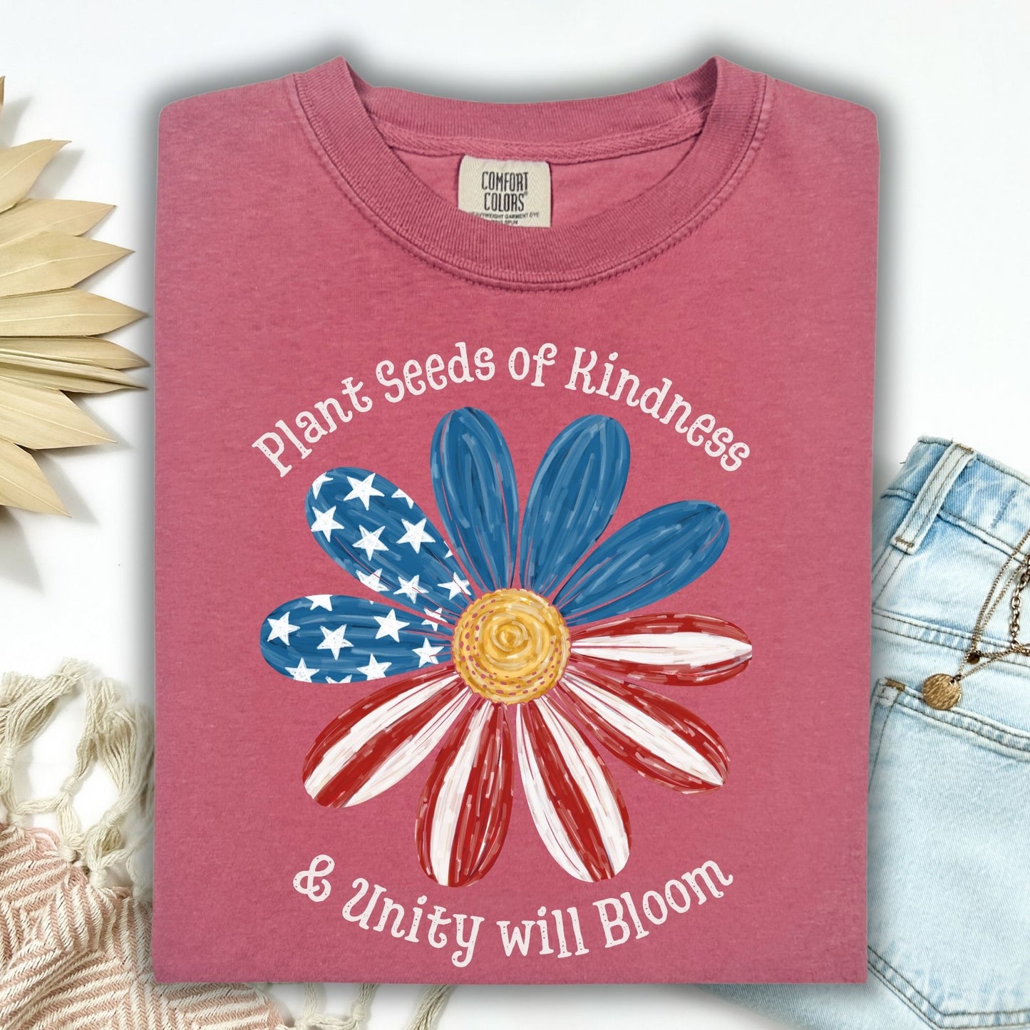 Brick Comfort Colors t-shirt with "Plant Seeds of Kindness & Unity will Bloom" and a daisy with a watercolor American flag.