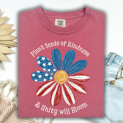 Brick Comfort Colors t-shirt with "Plant Seeds of Kindness & Unity will Bloom" and a daisy with a watercolor American flag.