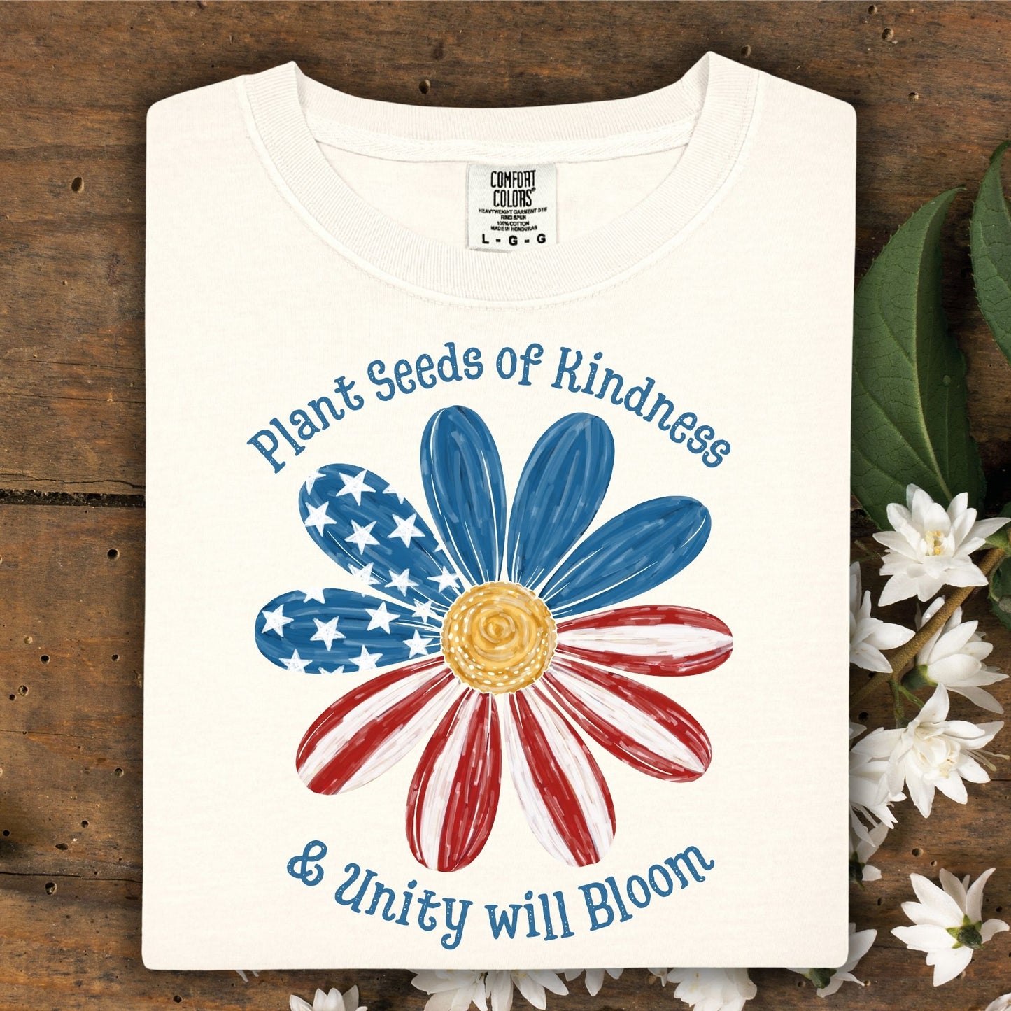Ivory Comfort Colors t-shirt with "Plant Seeds of Kindness & Unity will Bloom" and an American flag daisy.