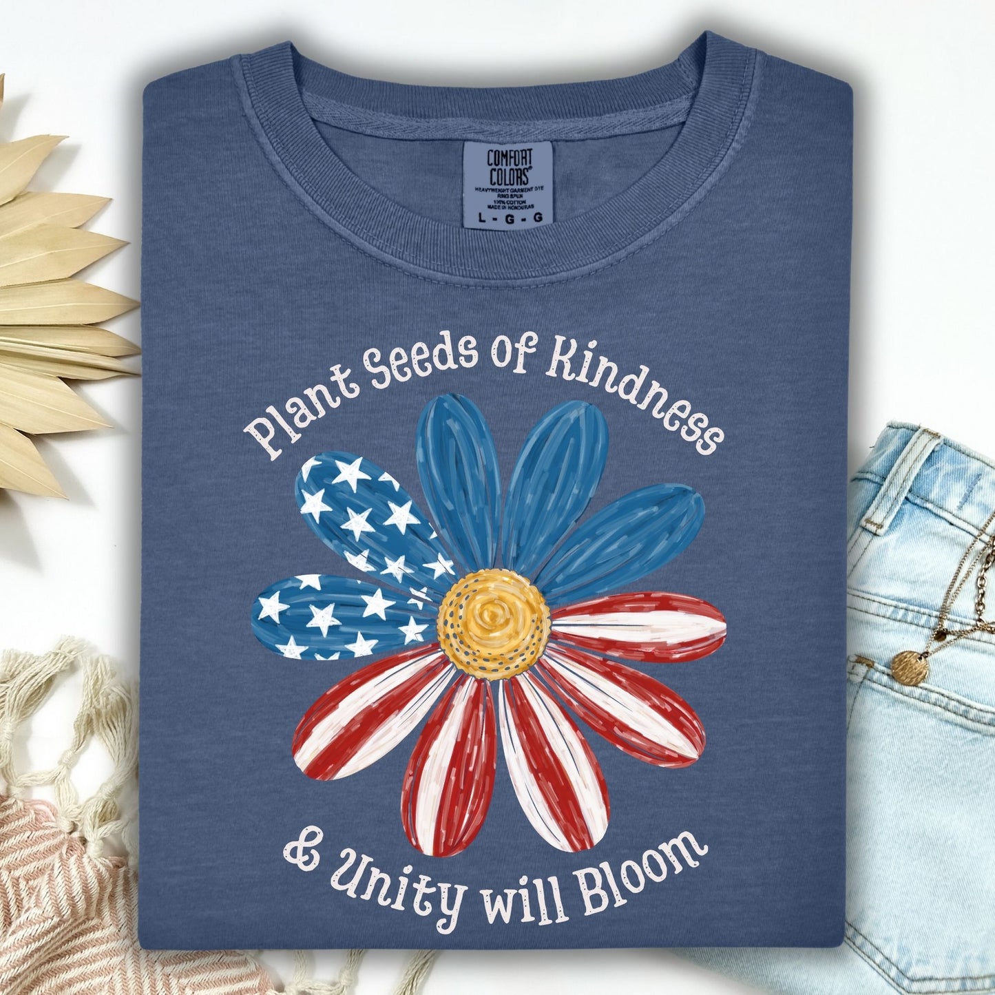 Denim Comfort Colors t-shirt with "Plant Seeds of Kindness & Unity will Bloom" and a watercolor American flag daisy.