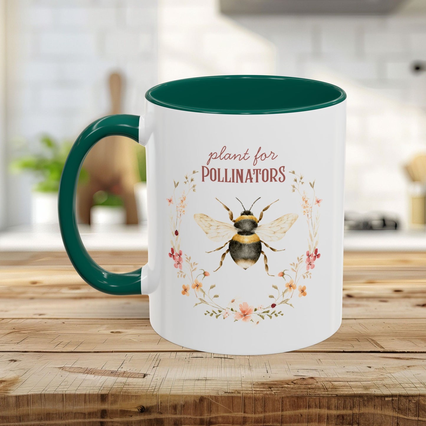 White ceramic mug with a green handle and interior, featuring a watercolor bee and "plant for Pollinators" text.