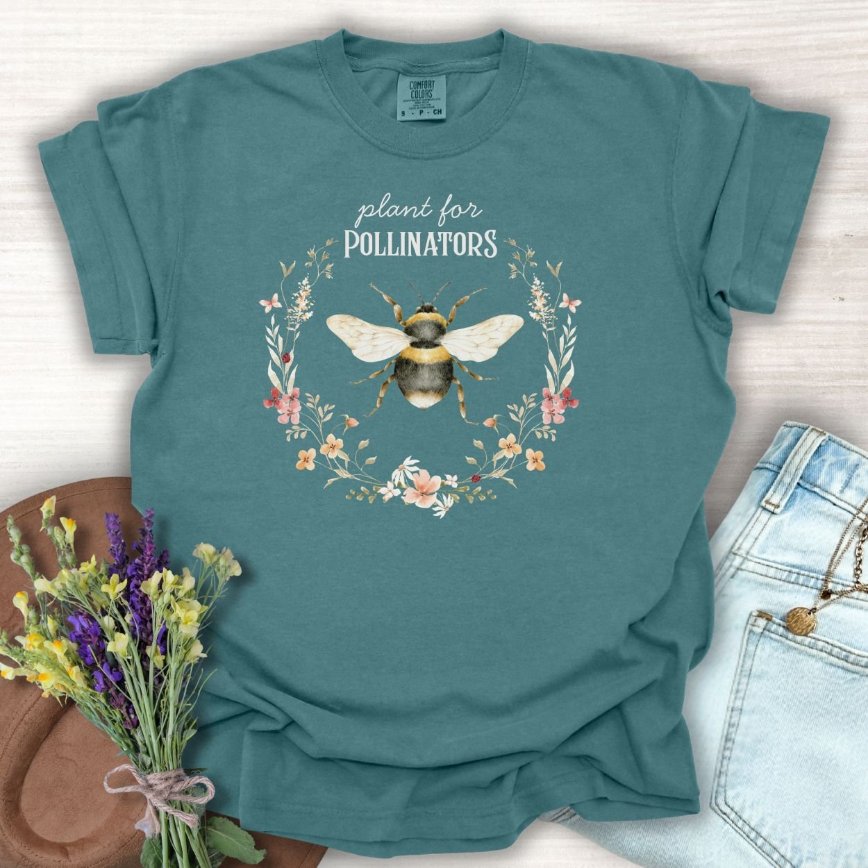 Blue Spruce garment-dyed cotton t-shirt with a hand-painted bumblebee and "Plant for Pollinators" text.