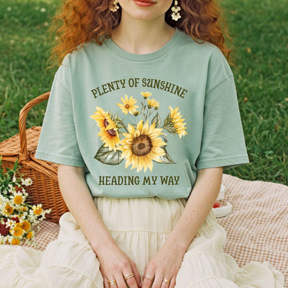 Relaxed-fit, garment-dyed sage green t-shirt with sunflowers and "Plenty of sunshine heading my way" text.