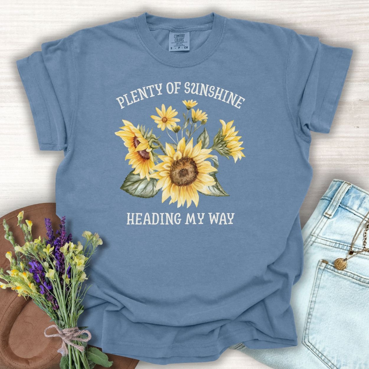 Blue Jean garment-dyed cotton t-shirt with "Plenty of Sunshine Heading My Way" text and sunflower graphic.