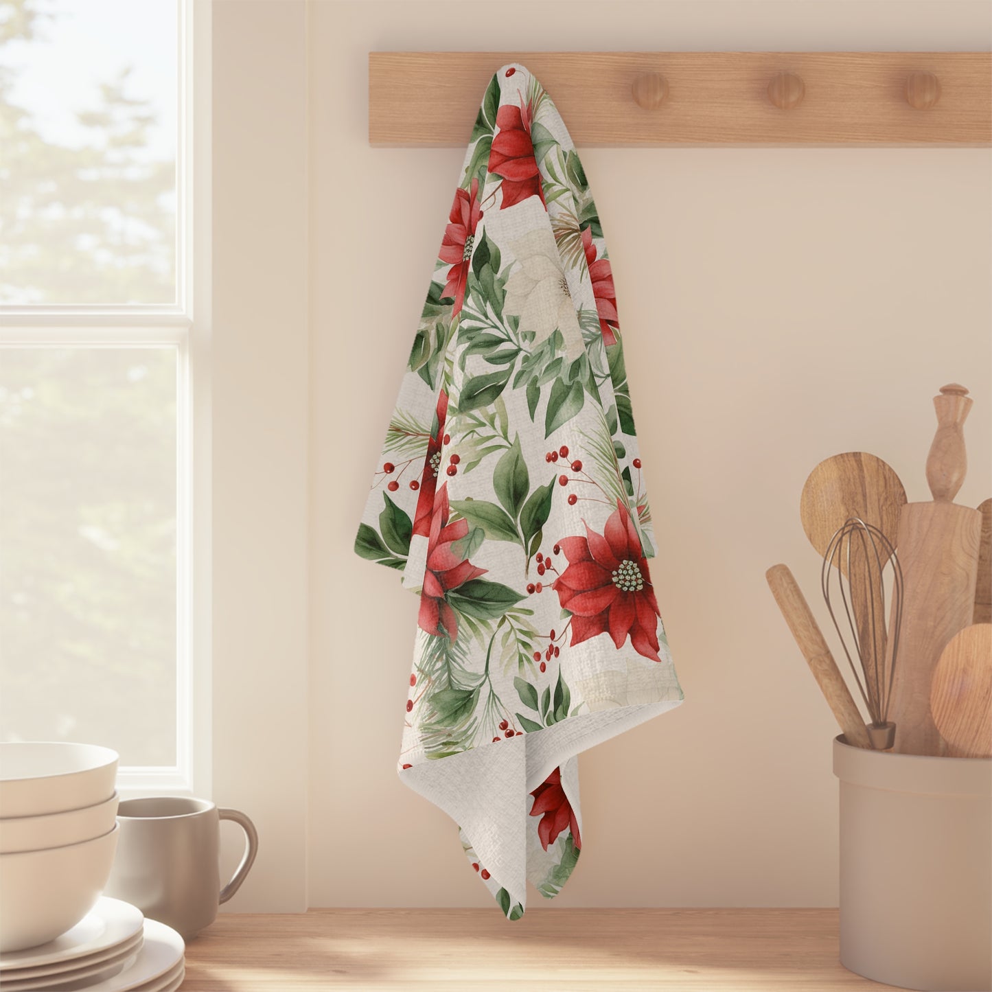 Holiday microfiber tea towel with a vibrant poinsettia, evergreen, and berry print, hanging on a wooden peg.