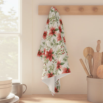 Watercolor poinsettia microfiber tea towel with red and green floral design hanging on a wooden peg rack.