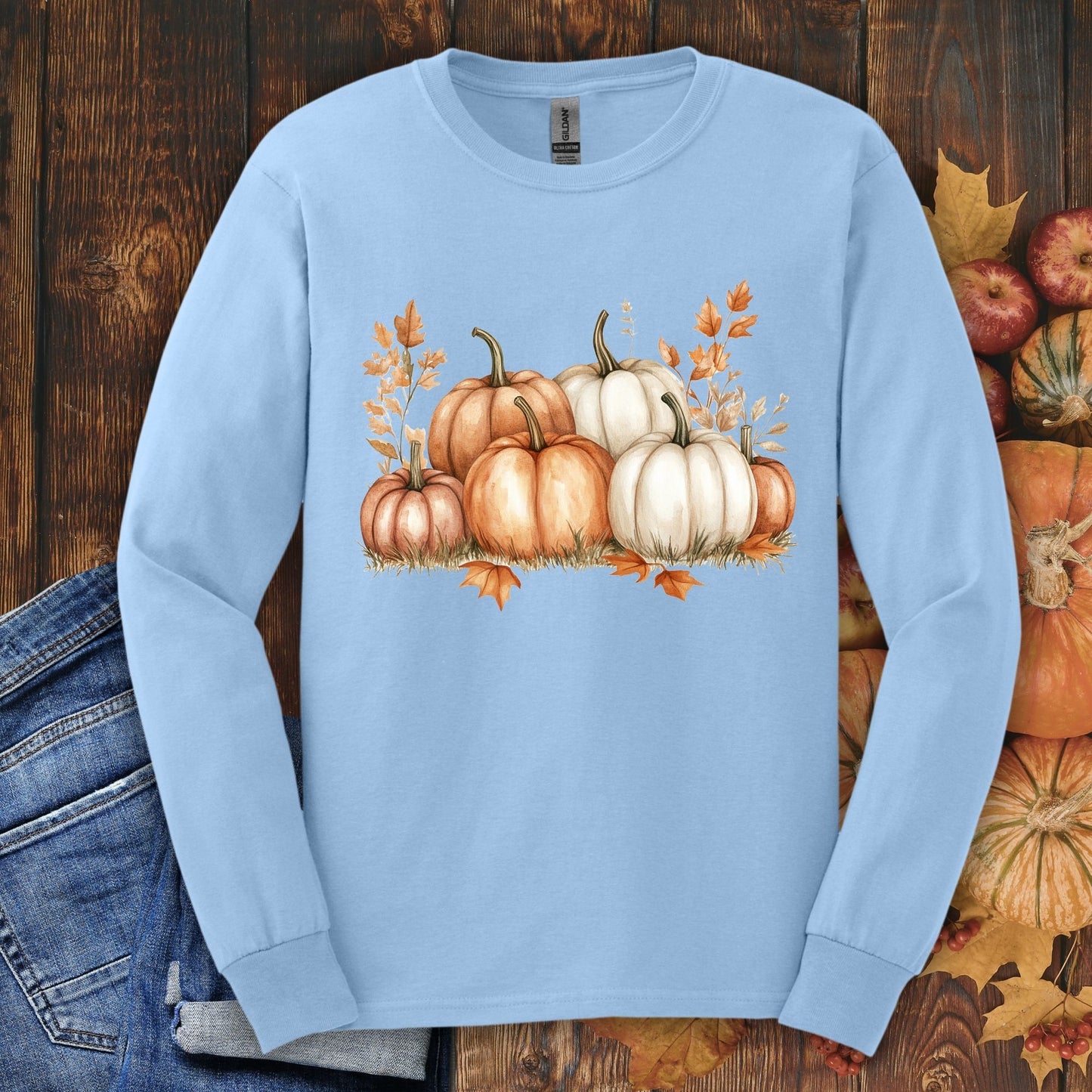 Light blue Gildan long sleeve tee with watercolor orange and white pumpkins, autumn leaves, and denim.