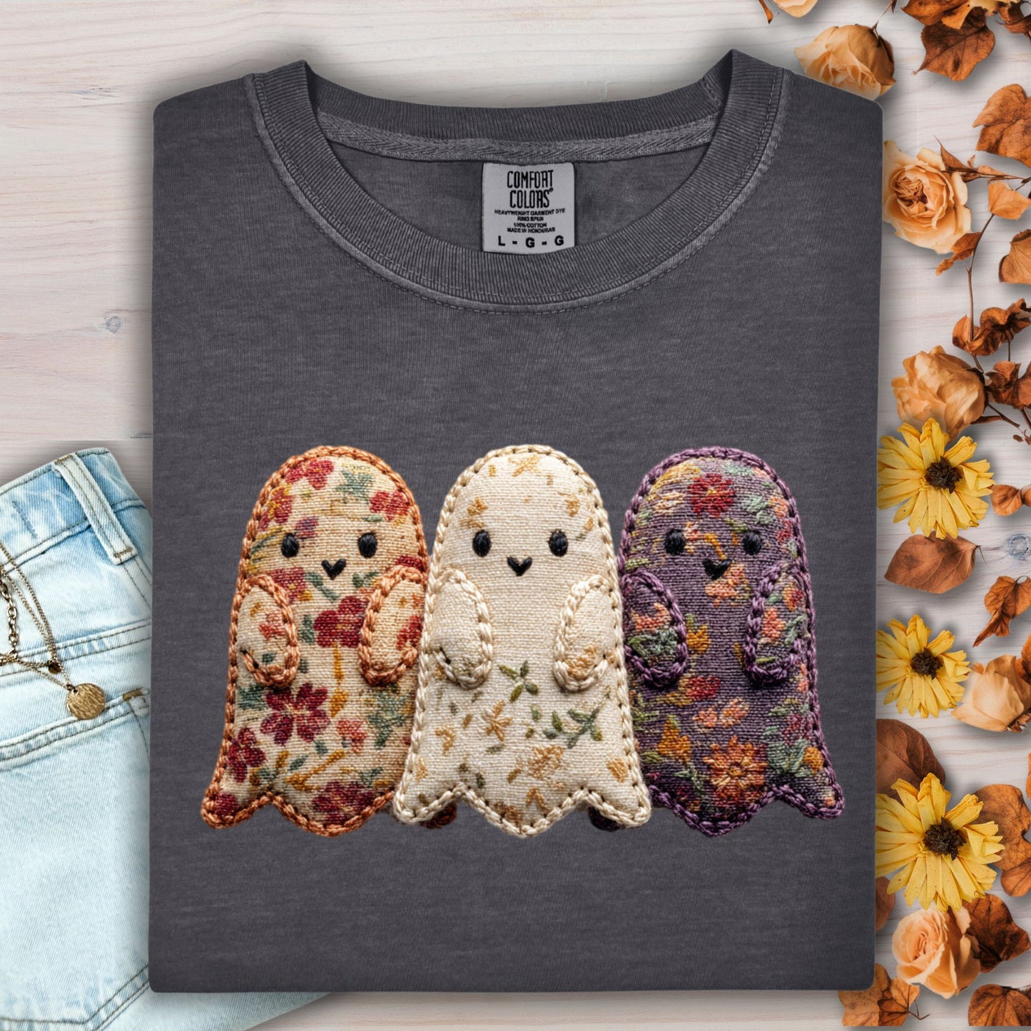 Pepper Comfort Colors t-shirt with three embroidered floral fabric ghosts, light wash jeans, and fall leaves.