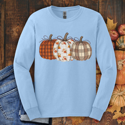 Light blue long sleeve tee with 3 cottagecore quilted pumpkins in plaid and floral patterns.