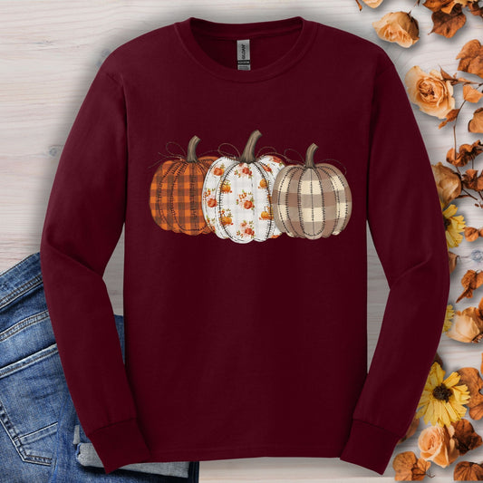 Maroon long sleeve tee with 3 cottagecore quilted pumpkins in plaid and floral patterns.