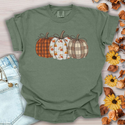 Moss green garment-dyed t-shirt with three patterned pumpkins in plaid, gingham, and tiny leaf motifs.