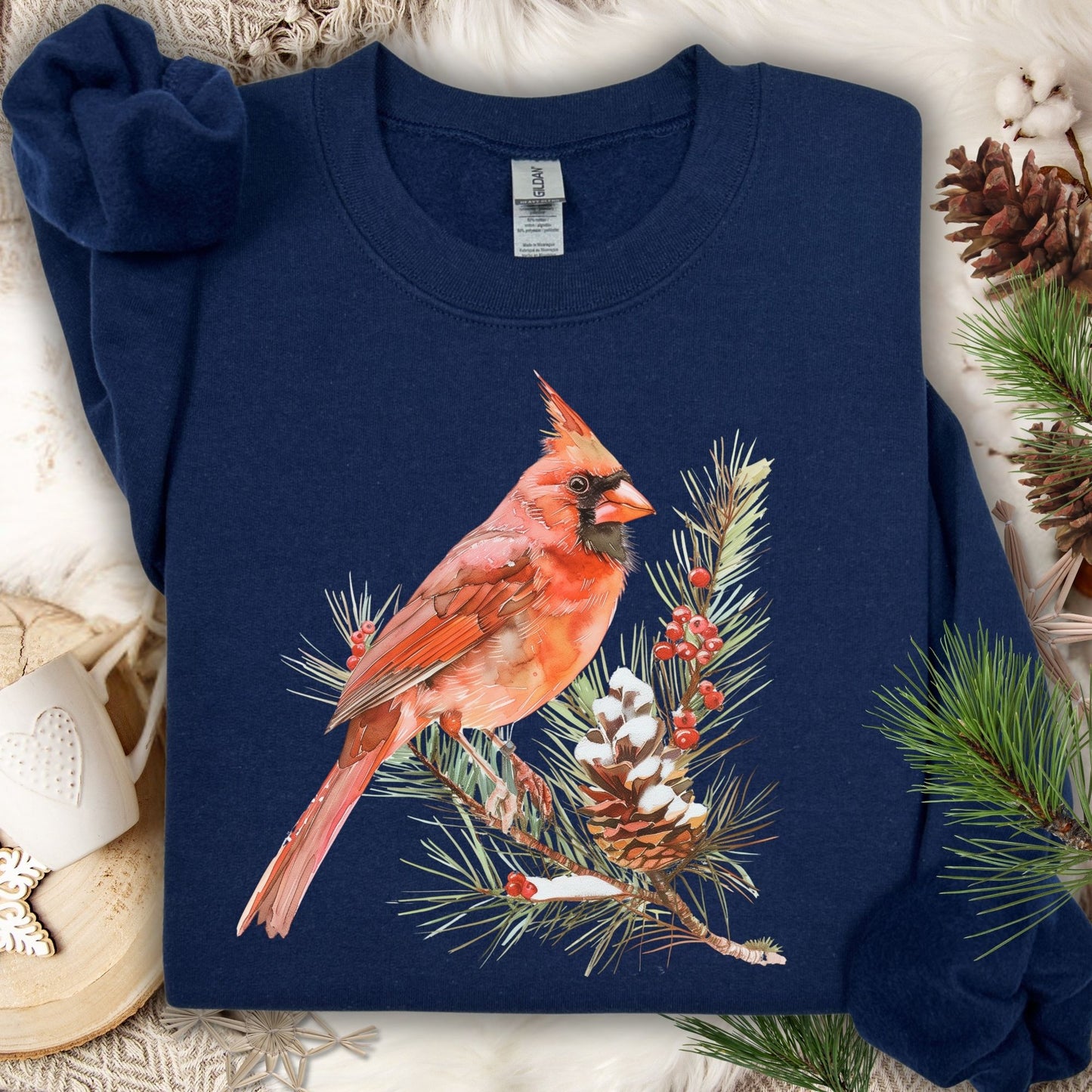 Navy sweatshirt with a red cardinal on a snowy evergreen branch illustration.