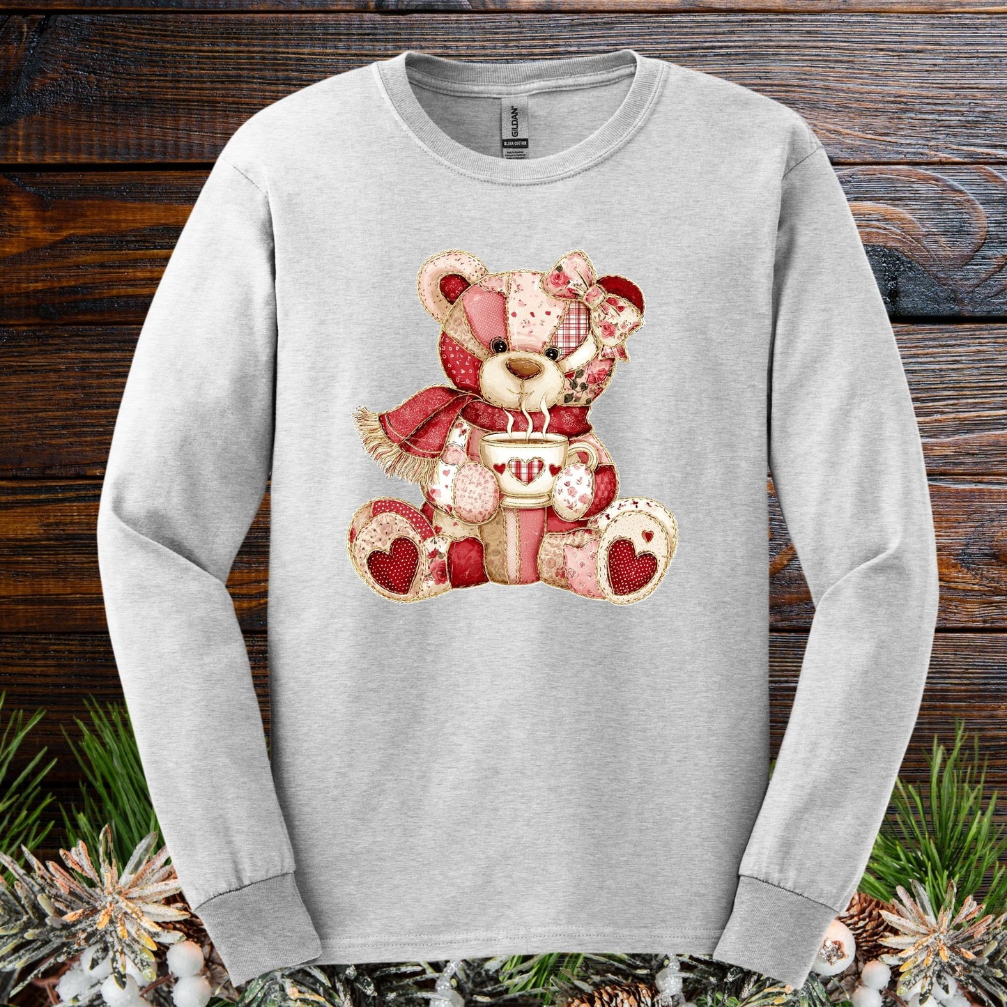 Ash long-sleeve tee with a patchwork country teddy bear holding hot chocolate.