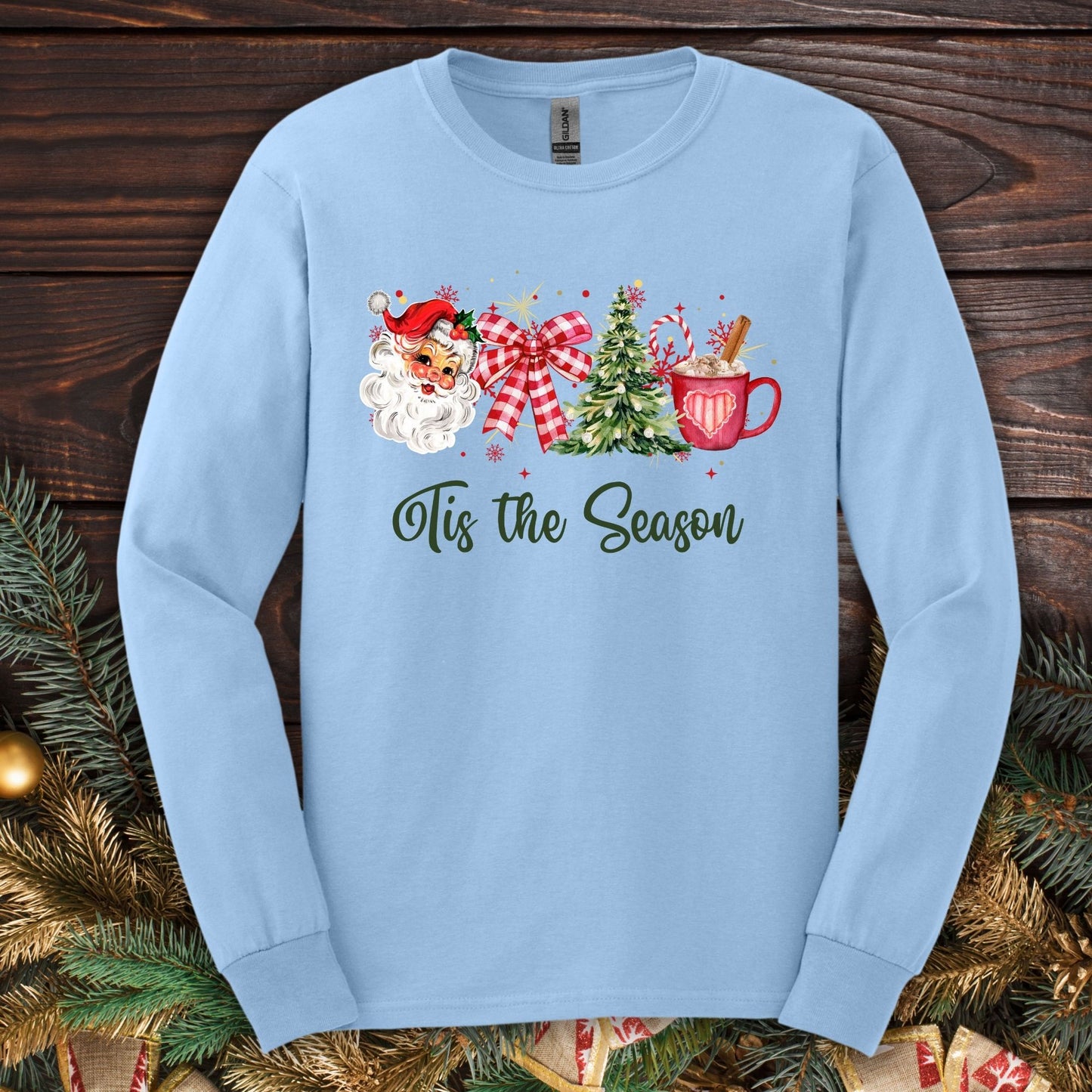 Light blue Gildan long sleeve tee with retro Santa, tree, ribbon, cocoa, and "'Tis the Season" graphic.