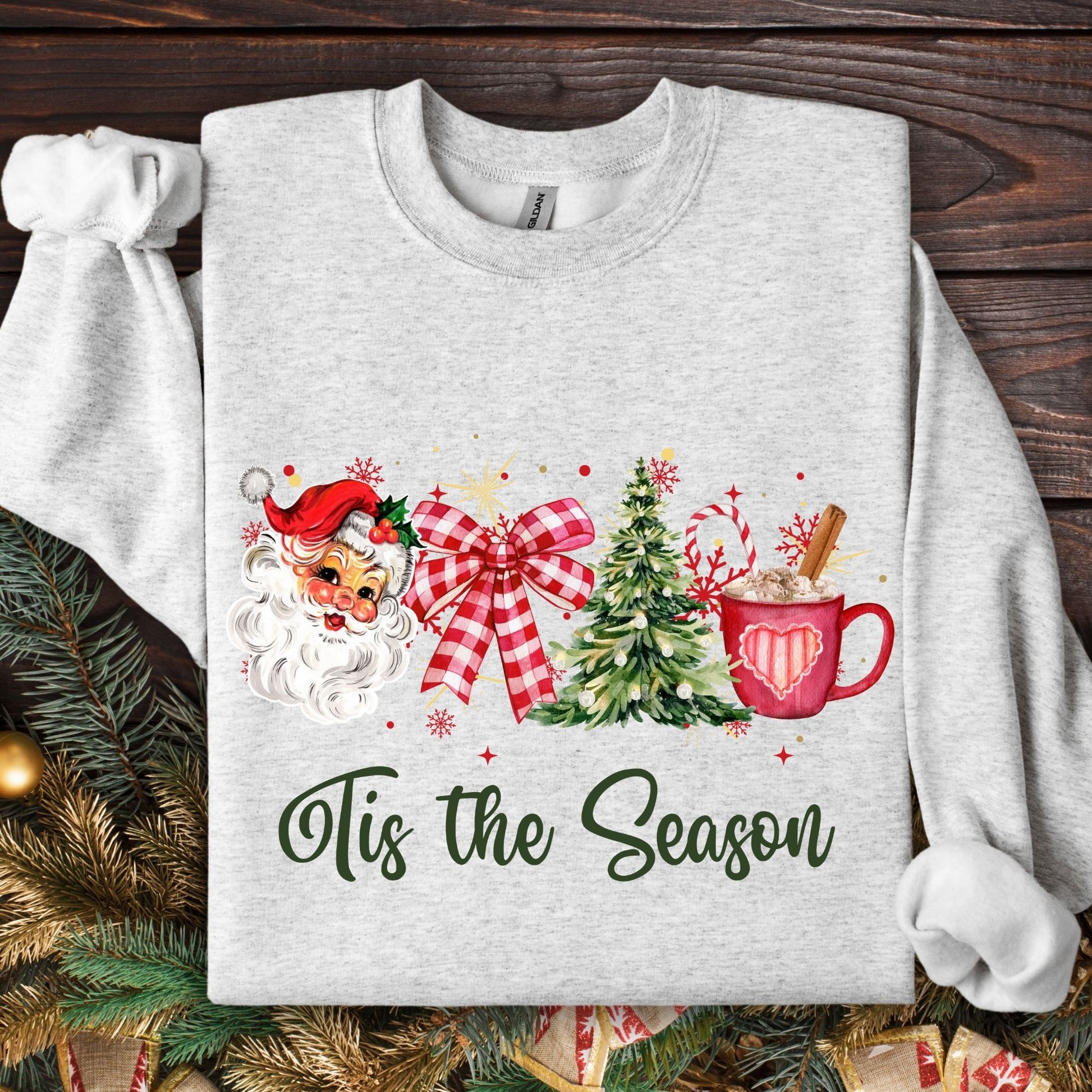 Ash Gildan sweatshirt with retro Santa, red bow, Christmas tree, cocoa mug, and "Tis the Season" text.