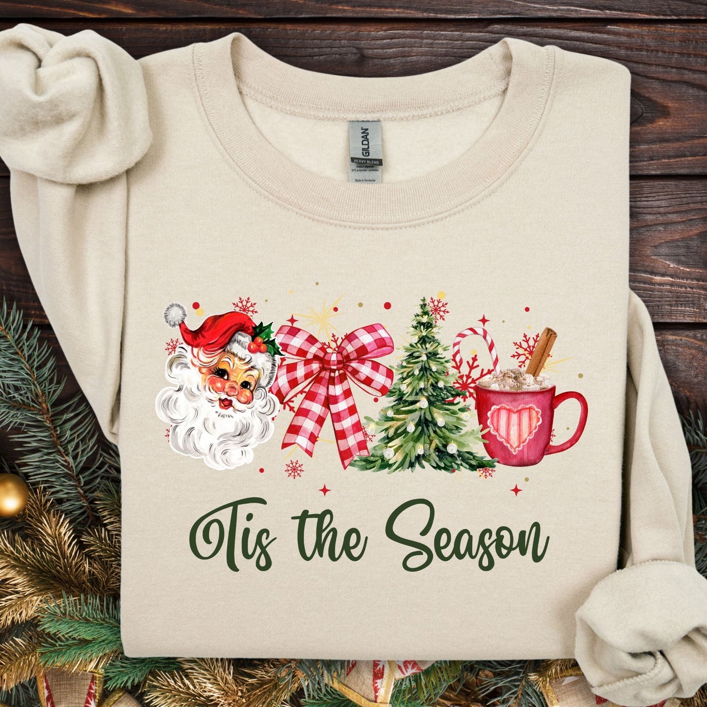 Sand Gildan sweatshirt with retro Santa, plaid bow, Christmas tree, cocoa, and "Tis the Season" text.