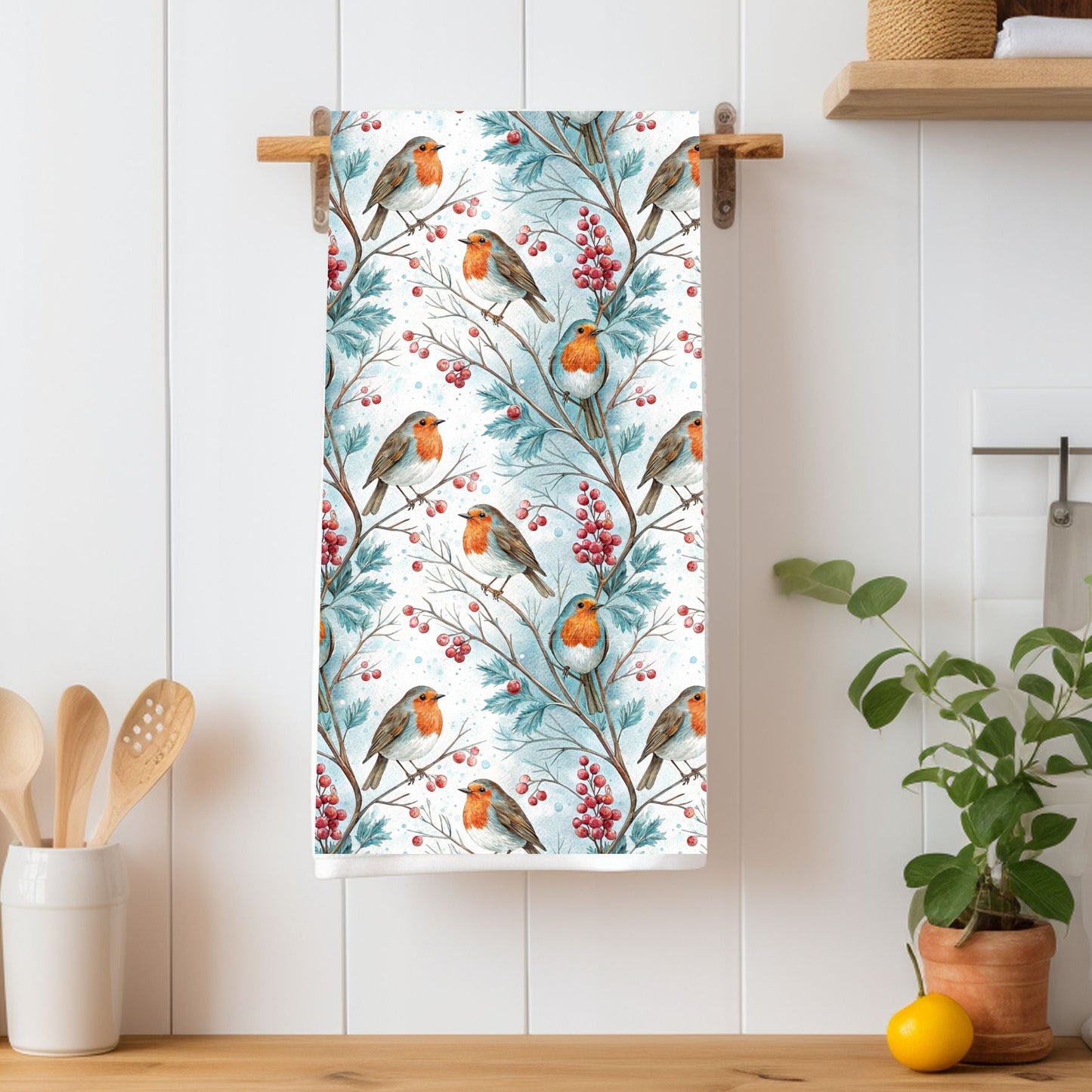 Microfiber tea towel with watercolor robins on holly branches and berries, hanging in a kitchen.