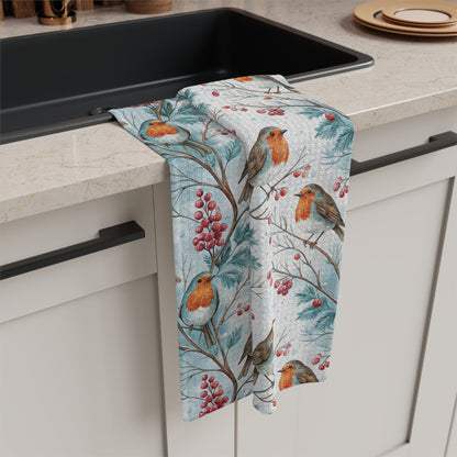 Microfiber tea towel with watercolor robins on holly branches and red berries, draped over a kitchen counter.