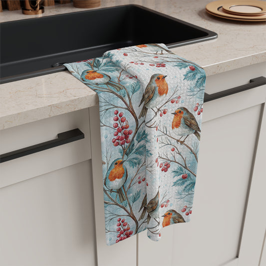 Microfiber tea towel with watercolor robins on holly branches and red berries, draped over a kitchen counter.