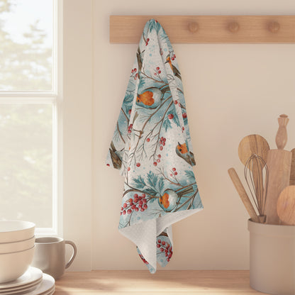 Microfiber tea towel with watercolor robins, holly berries, and blue winter branches hanging on a wooden peg.