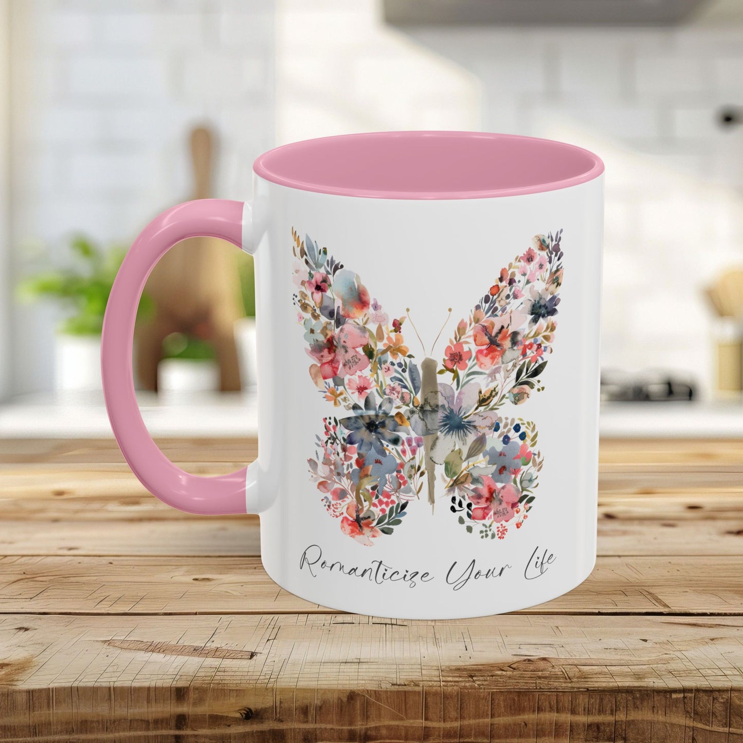 White ceramic mug with pink handle and interior, featuring a watercolor butterfly made of pink, blue, and green flowers.