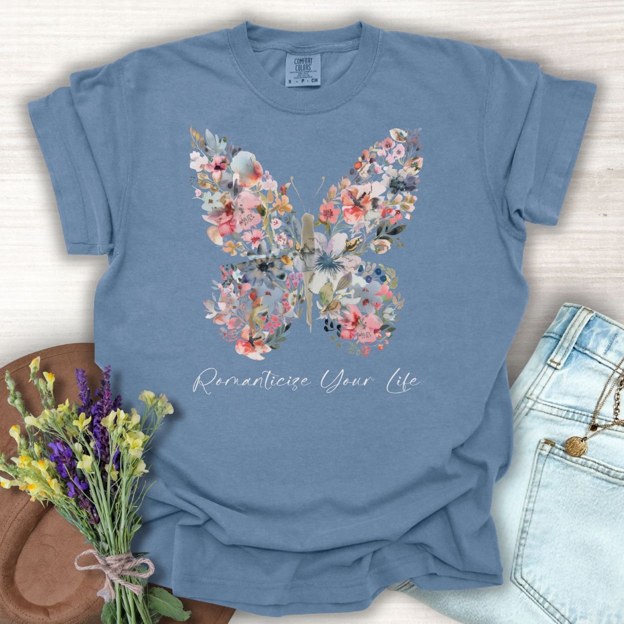 Blue Jean garment-dyed cotton t-shirt with a floral butterfly design and "Romanticize Your Life" text.