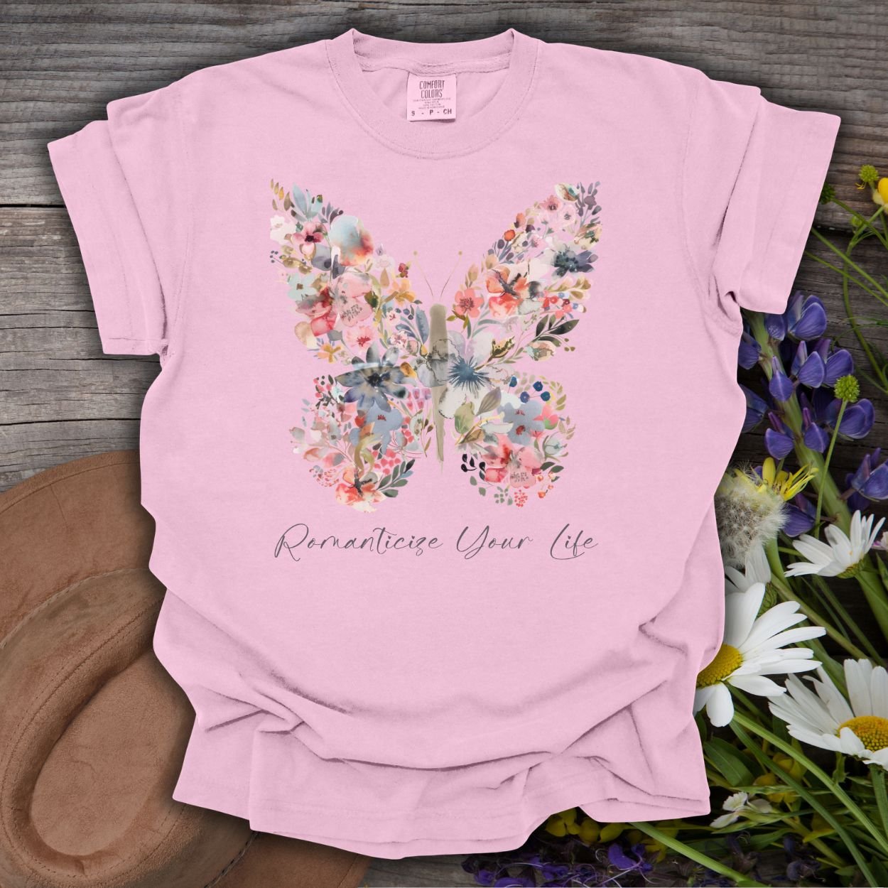Blossom pink garment-dyed cotton t-shirt with a floral butterfly design and "Romanticize Your Life" text.