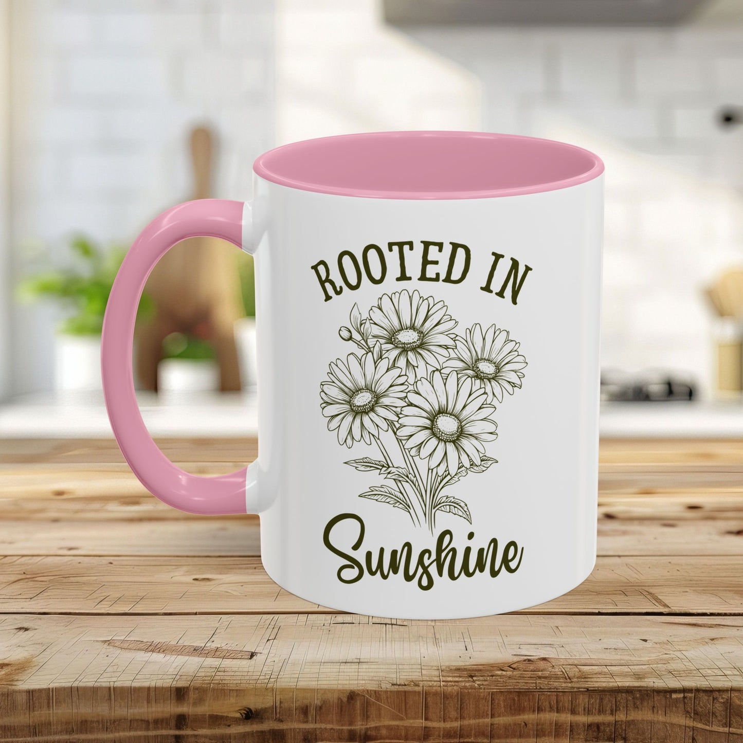White ceramic mug with pink interior and handle, featuring "Rooted in Sunshine" text and hand-drawn daisies.