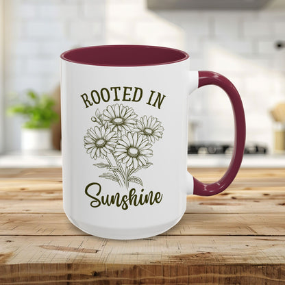 15oz glossy white ceramic mug with maroon interior/handle, "Rooted in Sunshine" text, and hand-drawn daisies.