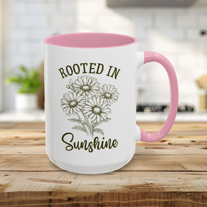 15oz white ceramic mug with pink interior/handle, "Rooted in Sunshine" text, and hand-drawn daisies.
