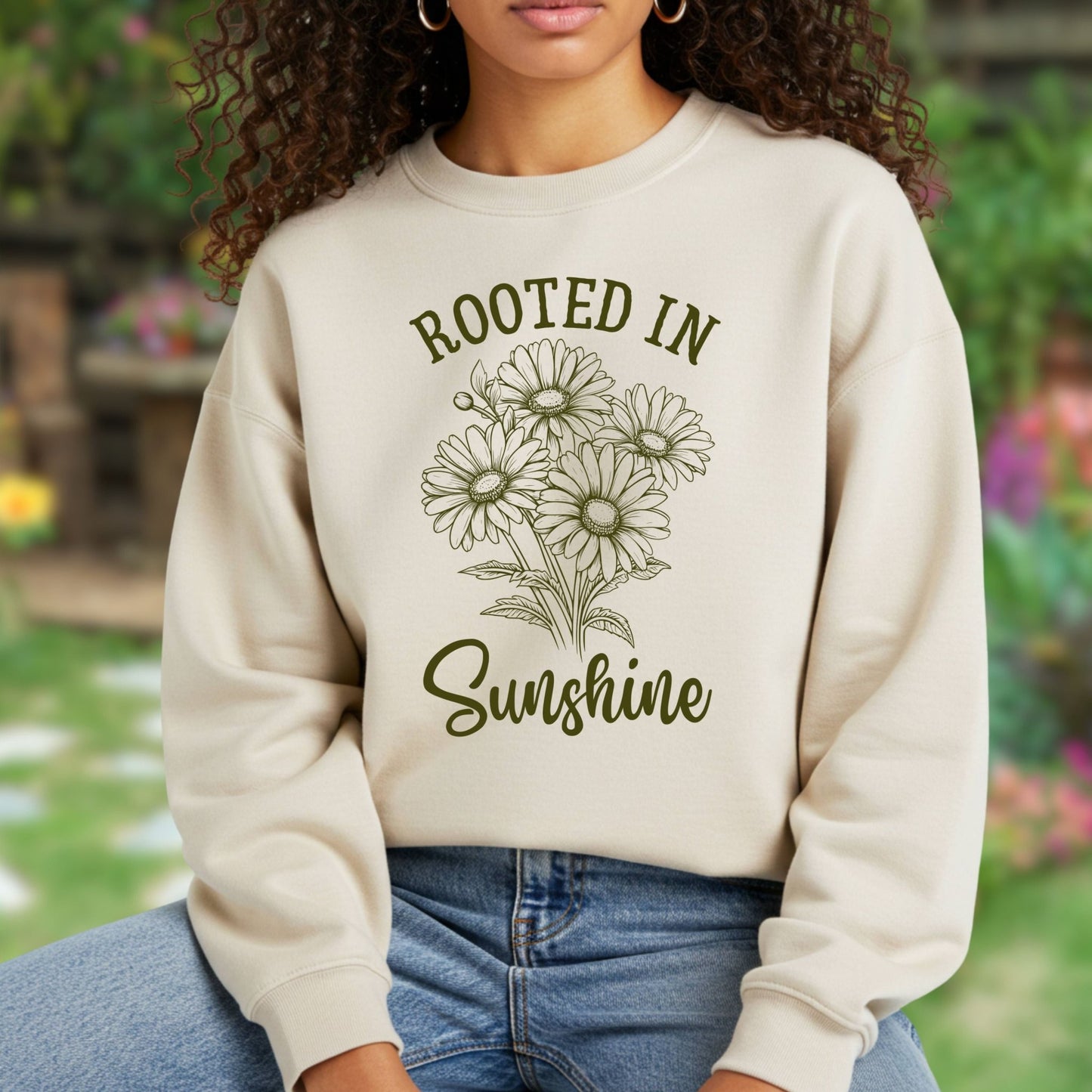 Beige unisex sweatshirt with "Rooted in Sunshine" text and a hand-drawn daisy bouquet design.