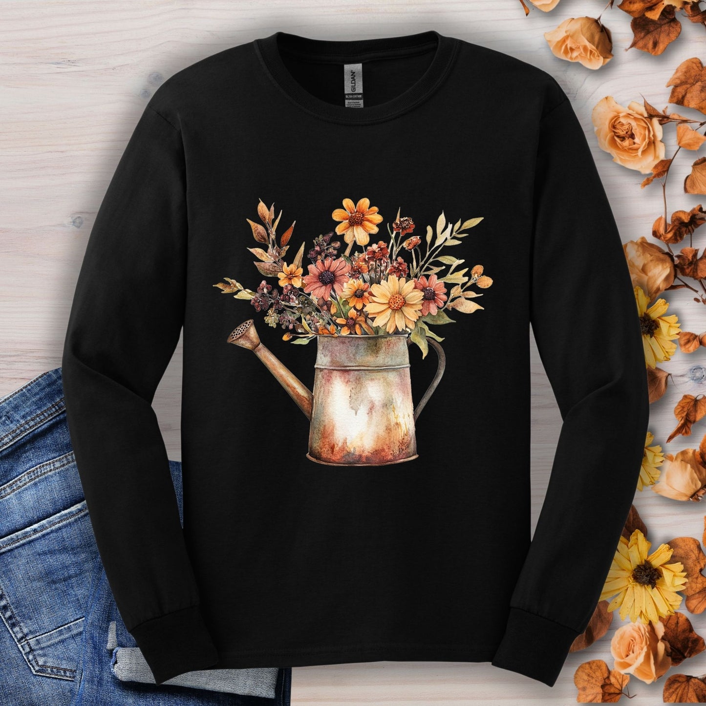 Black long sleeve tee with a watercolor watering can overflowing with autumn wildflowers.