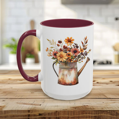 White ceramic mug with a maroon handle and interior, featuring a rustic watercolor watering can filled with autumn florals.