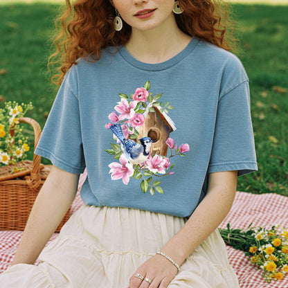 Garment-dyed blue t-shirt with a watercolor rustic birdhouse, blue jay, and pink floral design.