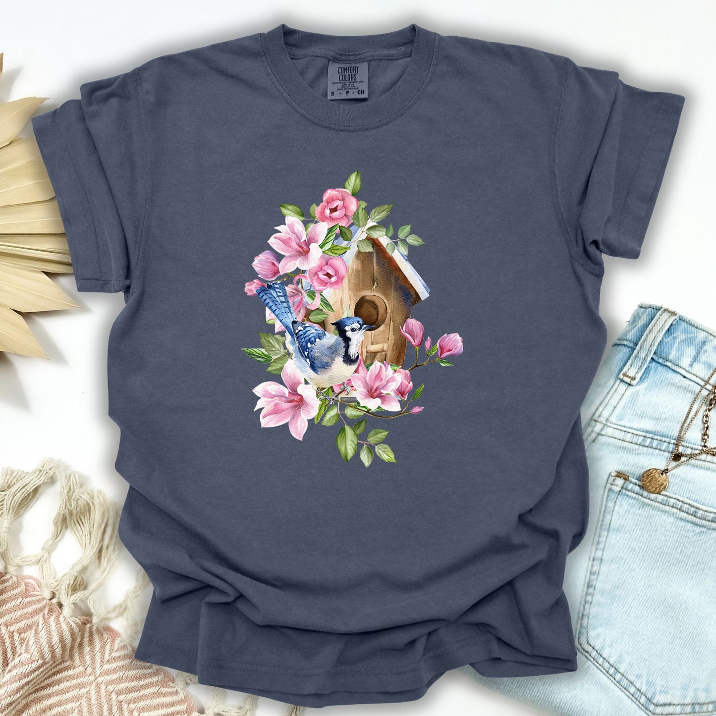 Denim S t-shirt with a watercolor blue jay on a rustic birdhouse with pink magnolia flowers.