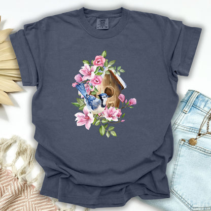 Denim S t-shirt with a watercolor blue jay on a rustic birdhouse with pink magnolia flowers.