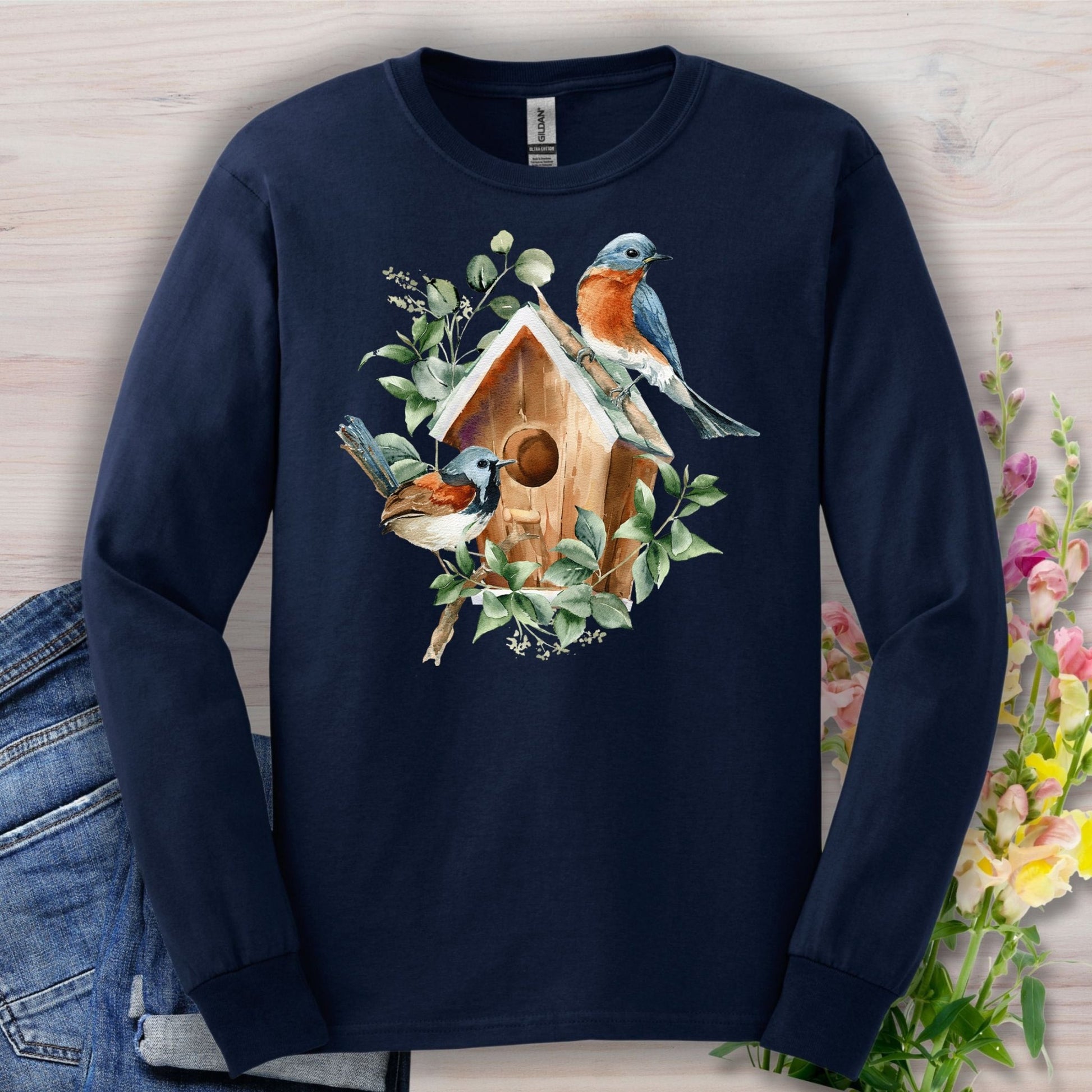 Navy long sleeve tee with a watercolor rustic birdhouse and two bluebirds on branches.