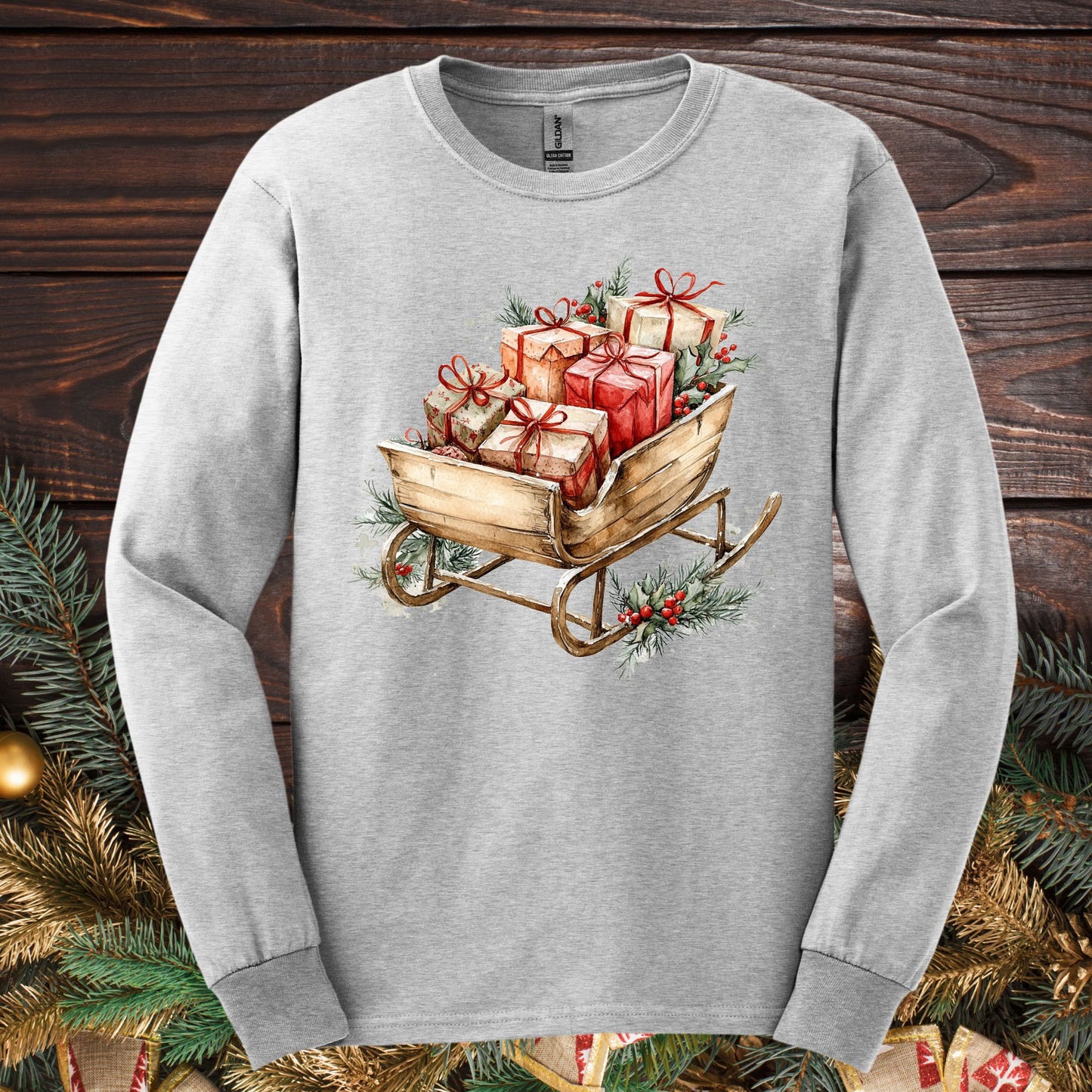 Ash gray Gildan long sleeve tee with a rustic watercolor Christmas sleigh full of gifts and greenery.