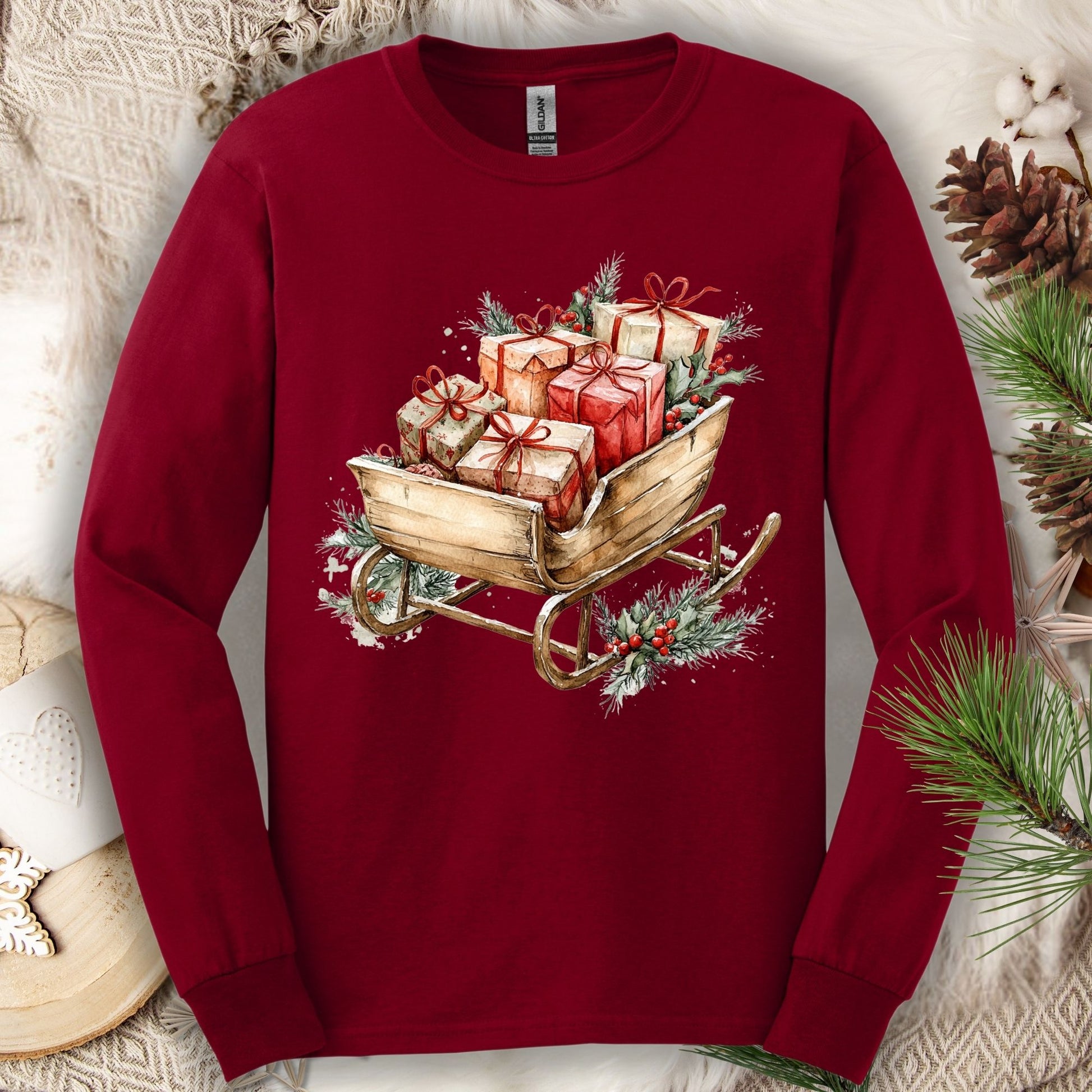 Cardinal Red Gildan long sleeve tee with a watercolor rustic Christmas sleigh full of gifts and greenery.