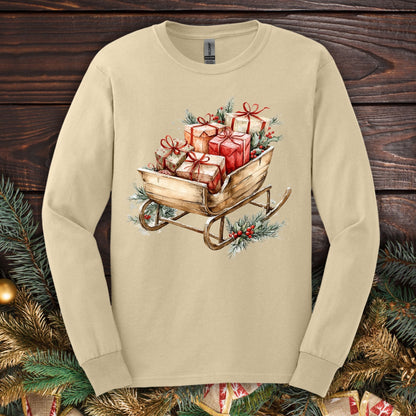 Sand Gildan long sleeve tee with a rustic watercolor Christmas sleigh full of gifts and greenery.