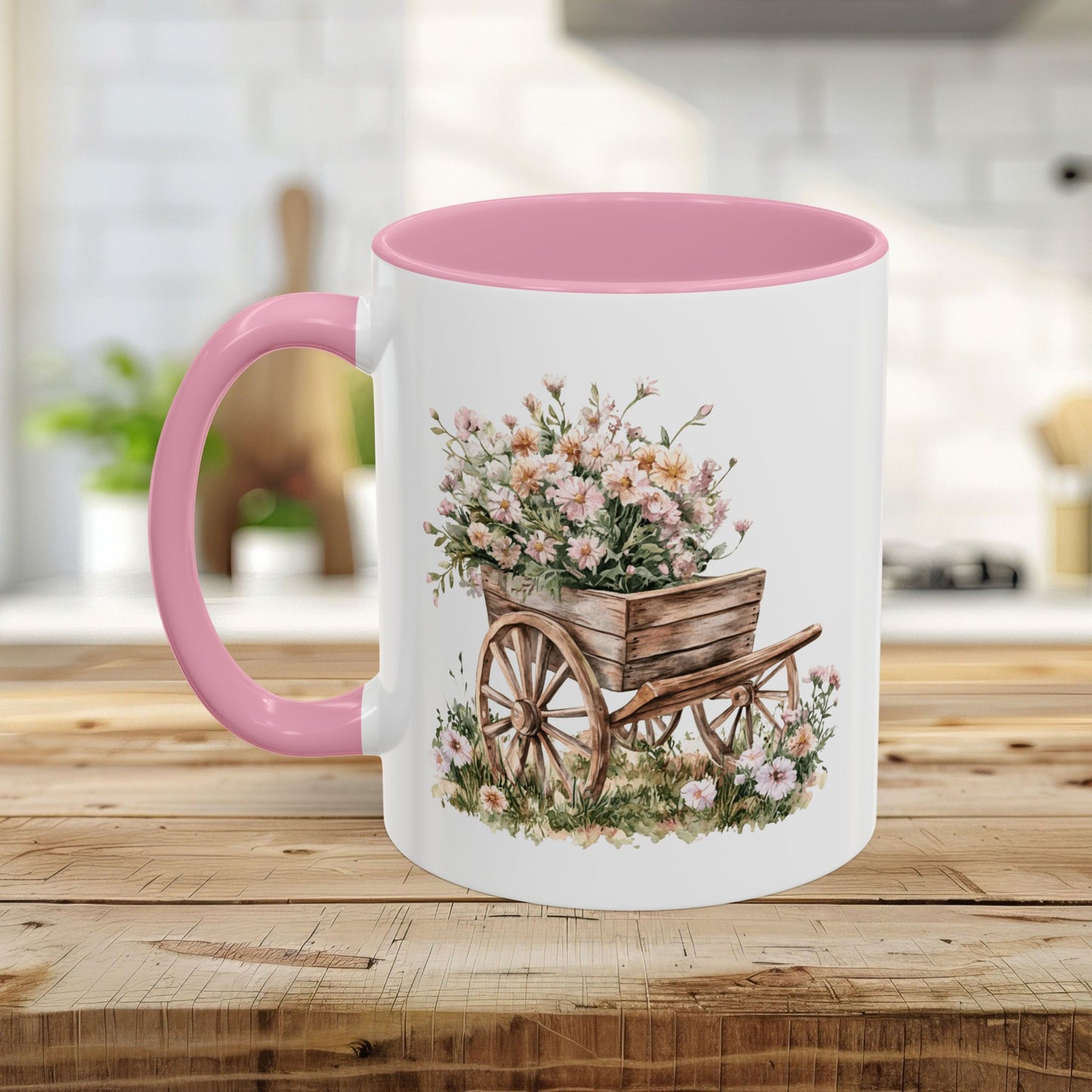 White ceramic mug with pink interior and handle, featuring a watercolor wheelbarrow overflowing with pink flowers.