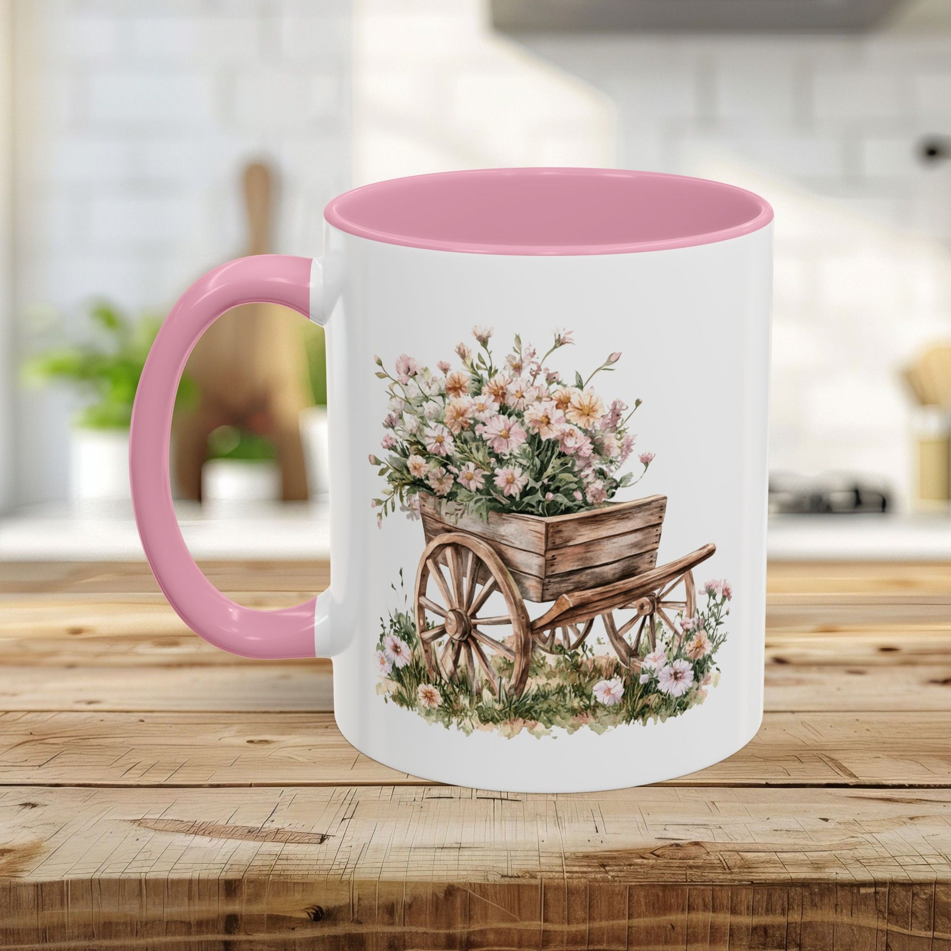 White ceramic mug with pink interior and handle, featuring a watercolor wheelbarrow overflowing with pink flowers.