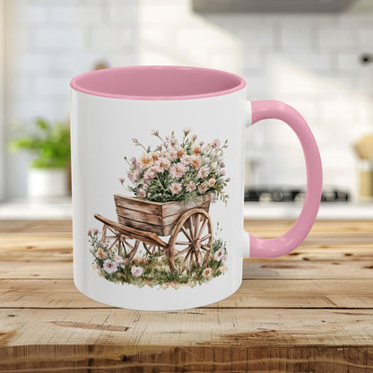 11oz ceramic mug with pink handle and interior, featuring a watercolor wheelbarrow overflowing with pink blooms.