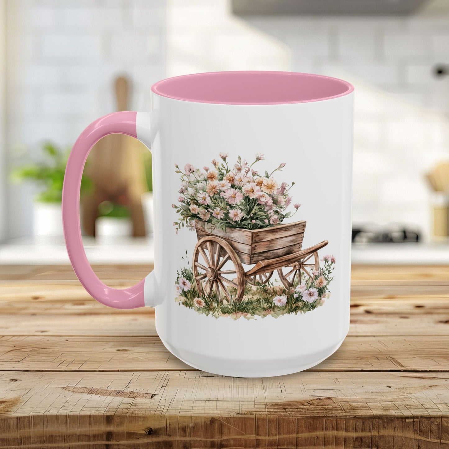 White ceramic mug with pink interior and handle, featuring a watercolor wheelbarrow overflowing with pink blooms.